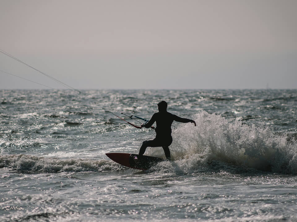 A silhouette of a guy kite surfing.